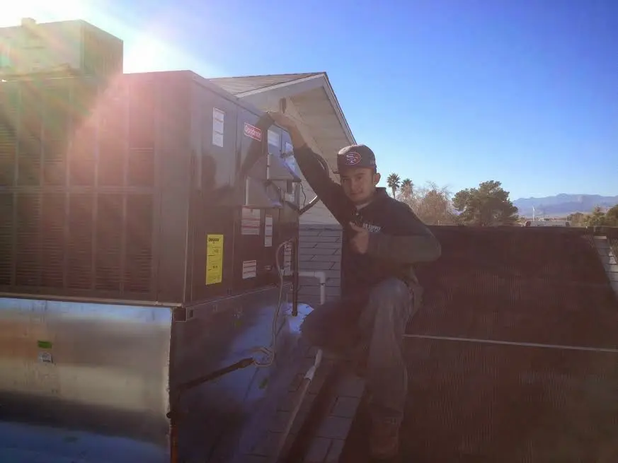 HVAC technician performing Air Duct Cleaning on a rooftop unit in Anderson